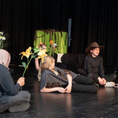 Jugendliche sitzen bei einer Theaterprobe auf einer B&uuml;hne.