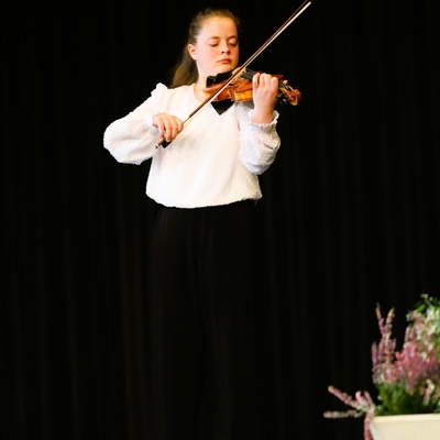 Eine junge Musikerin spielt Geige auf einer B&uuml;hne.