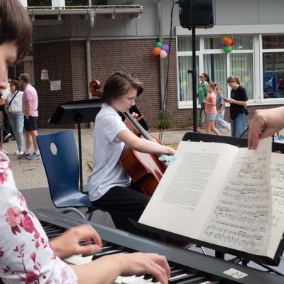 Eine Person spielt Klavier, Notenst&auml;nder und Publikum sind im Bild.