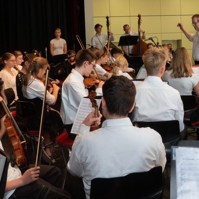 Sch&uuml;lerorchester spielt gemeinsam auf einer B&uuml;hne.