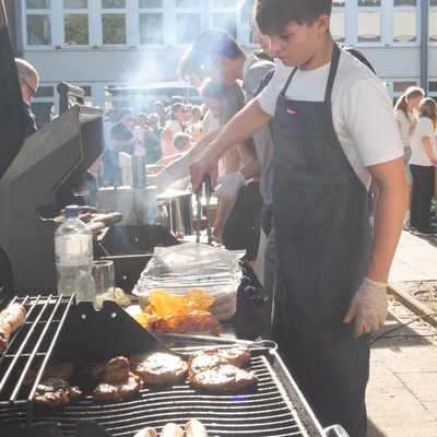 Eine Person grillt Essen an einem Grillstand im Freien.