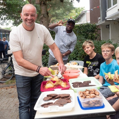 Sch&uuml;ler und Lehrer an einem Essensstand auf dem Schulhof.