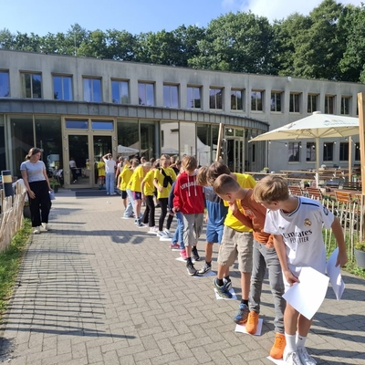 Kinder stehen in einer langen Reihe vor einem Geb&auml;ude im Freien.