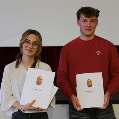 Zwei Jugendliche halten Urkunden und posieren nebeneinander.