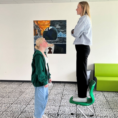 Zwei Sch&uuml;lerinnen stehen sich bei einer Unterrichts&uuml;bung gegen&uuml;ber, eine davon erh&ouml;ht auf einem Stuhl..