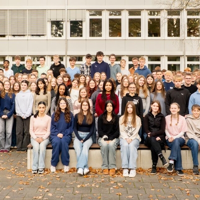 Gro&szlig;e Gruppe von Sch&uuml;lerinnen und Sch&uuml;lern posiert gemeinsam mit Lehrkr&auml;ften im Freien.