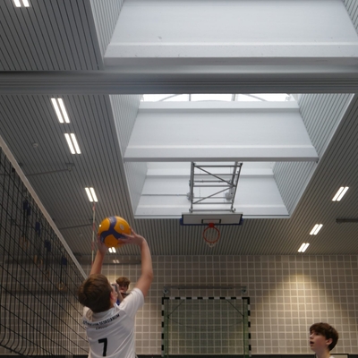 Spieler wirft den Volleyball zum Aufschlag in einer Sporthalle hoch.