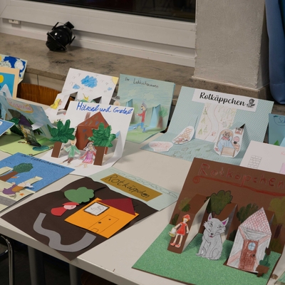 Tisch mit aufgeklappten Pop-up-B&uuml;chern und gestalteten Buchseiten.