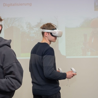 Zwei Jugendliche nutzen eine VR-Brille bei einer Pr&auml;sentation in einem Innenraum.