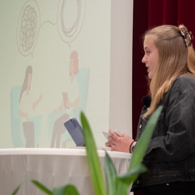 Eine Jugendliche spricht bei einer Pr&auml;sentation an einem Stehtisch.