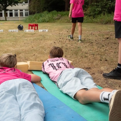 Kinder liegen bei einem Spiel im Freien auf Matten.