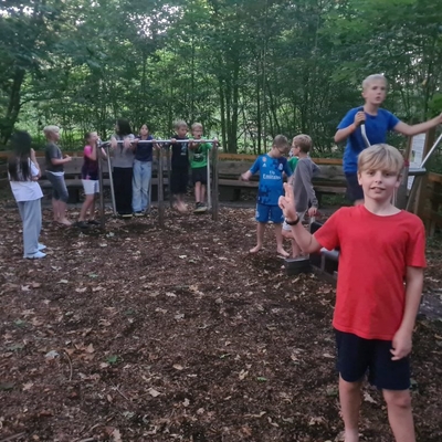 Kinder bewegen sich auf einem Outdoor-Parcours im Waldgel&auml;nde.