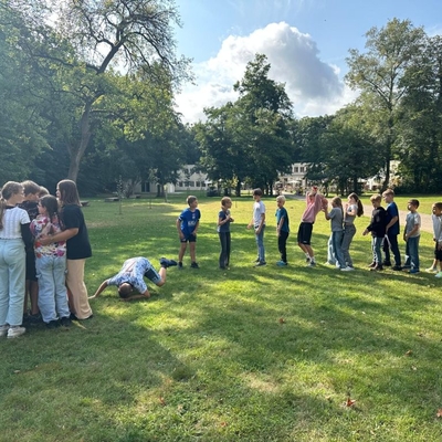 Kinder und Jugendliche l&ouml;sen gemeinsam eine Aufgabe auf einer Wiese.