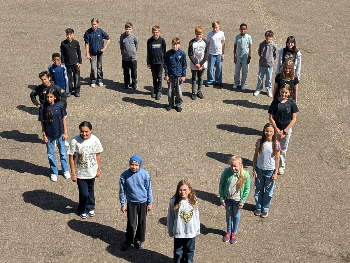 Sch&uuml;lerinnen und Sch&uuml;ler stehen in Herzformation auf dem Schulhof