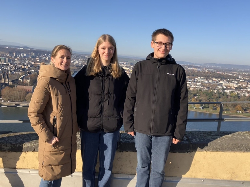 Drei Personen stehen auf einer Aussichtsterrasse mit Blick &uuml;ber Koblenz.