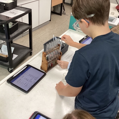 Sch&uuml;ler arbeitet an einem Experimentiertisch mit Tablet und Laborger&auml;t.