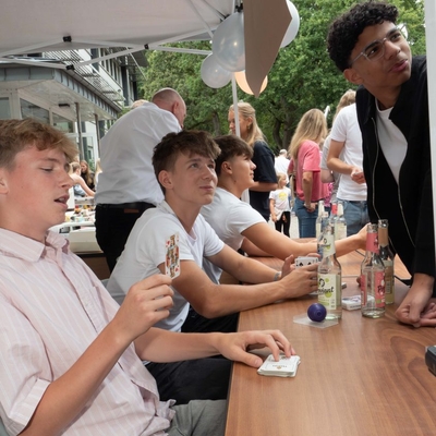 Jugendliche an einem Stand mit mehreren Kartendecks auf dem Tisch.