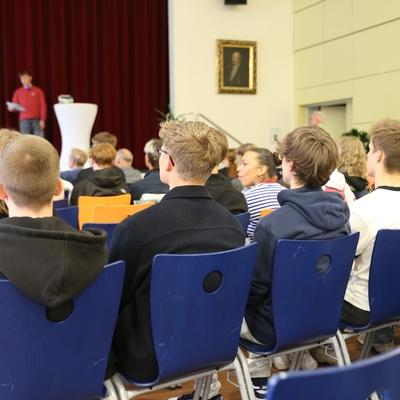 Blick von hinten auf sitzendes Publikum w&auml;hrend einer Pr&auml;sentation.