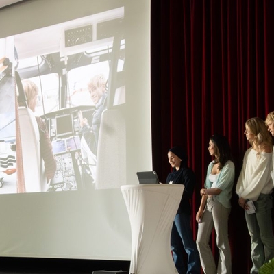 F&uuml;nf Sch&uuml;lerinnen und Sch&uuml;ler pr&auml;sentieren auf einer B&uuml;hne.