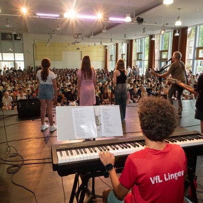 Musizierende treten in einer Kirche vor Publikum auf, ein Keyboard ist im Vordergrund.