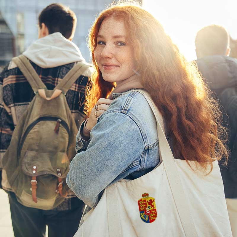 L&auml;chelnde Sch&uuml;lerin mit Rucksack blickt &uuml;ber die Schulter.