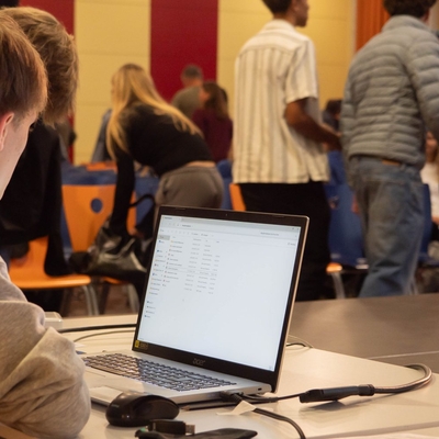 Laptop im Vordergrund, im Hintergrund der Veranstaltungsraum w&auml;hrend einer Pr&auml;sentation.