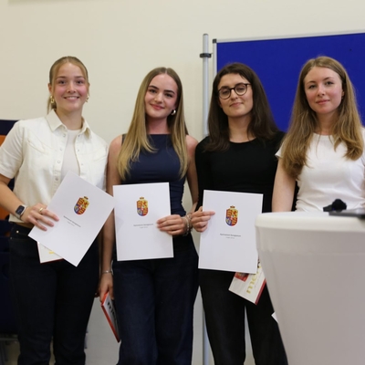 Vier Jugendliche halten Urkunden und posieren f&uuml;r ein Gruppenfoto.