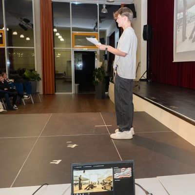 Jugendlicher pr&auml;sentiert auf einer B&uuml;hne, im Vordergrund steht ein Laptop.