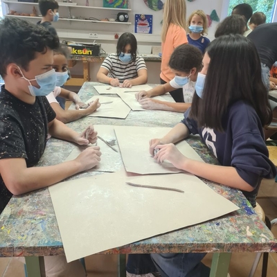 Kinder sitzen gemeinsam an einem Tisch und arbeiten an einer Aufgabe.