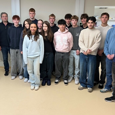 Eine Sch&uuml;lergruppe posiert im Aufwachraum eines Herzkatheterlabors mit dem Chefarzt und dem Lehrer.