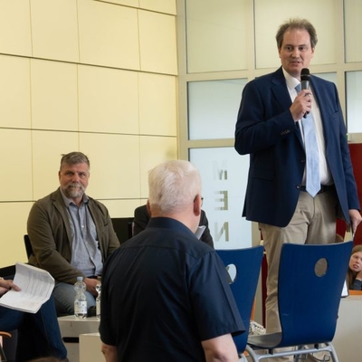 Der Schulleiter begr&uuml;&szlig;t die Teilnehmenden der Podiumsdiskussion sowie das Publikum in der Mensa.