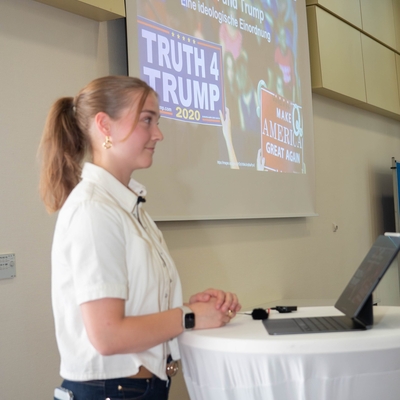 Eine Jugendliche h&auml;lt einen Vortrag an einem Stehtisch mit Laptop.