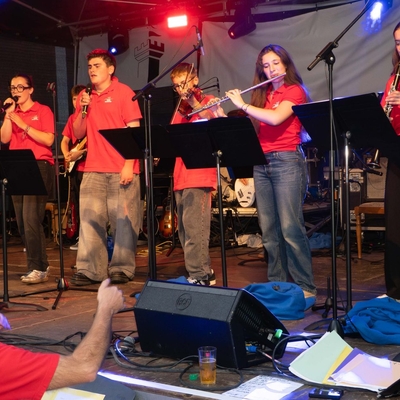 Mehrere Musiker spielen gemeinsam auf einer B&uuml;hne bei einem Konzert.