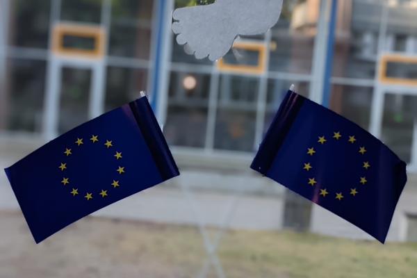 Zwei gekreuzte Europaflaggen, dar&uuml;ber eine Friedenstaube aus Papier