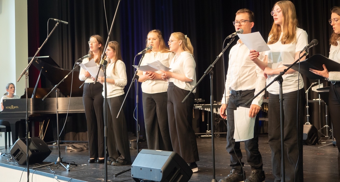 Ein Schulchor singt gemeinsam auf einer B&uuml;hne.