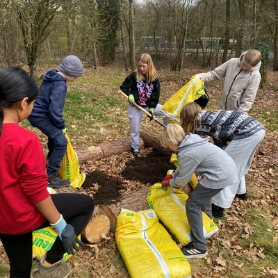 Gruppe von Sch&uuml;lerinnen und Sch&uuml;lern arbeitet mit gelben S&auml;cken bei einer Aktion im Freien.