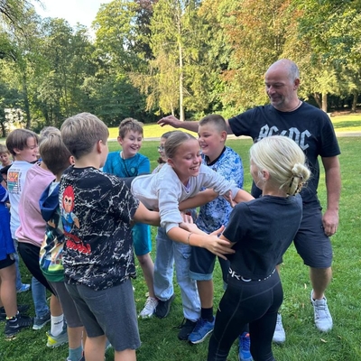 Kinder und ein Erwachsener machen gemeinsam eine Vertrauens- oder Kooperations&uuml;bung.