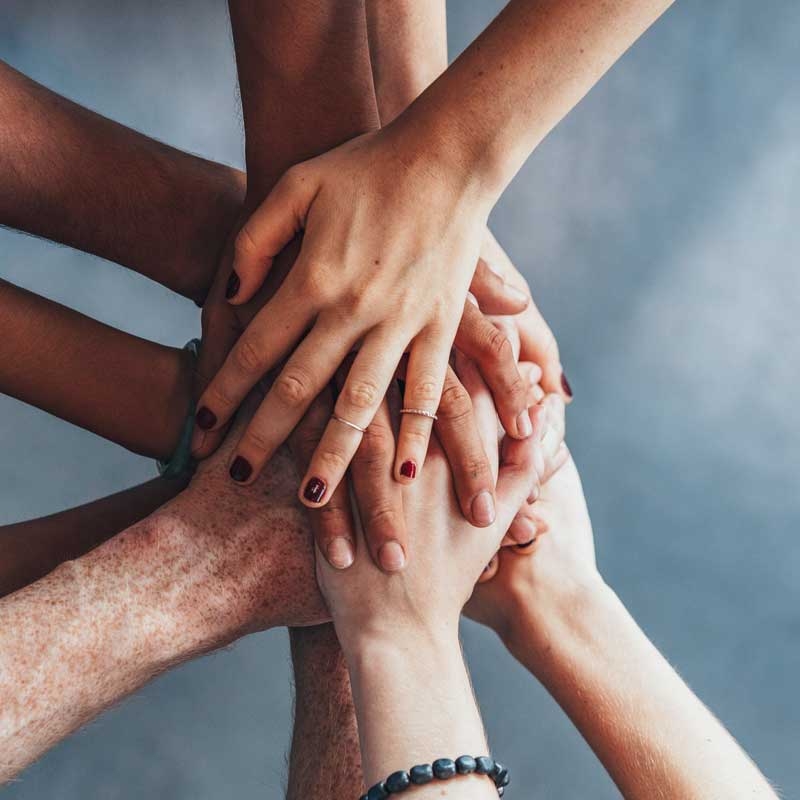 Mehrere H&auml;nde &uuml;bereinander als Zeichen f&uuml;r Zusammenhalt.