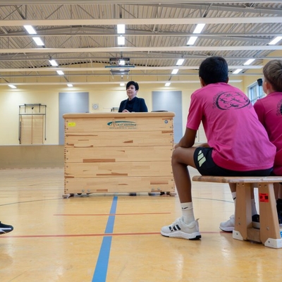 Eine Person spricht an einem Rednerpult in einer Sporthalle.