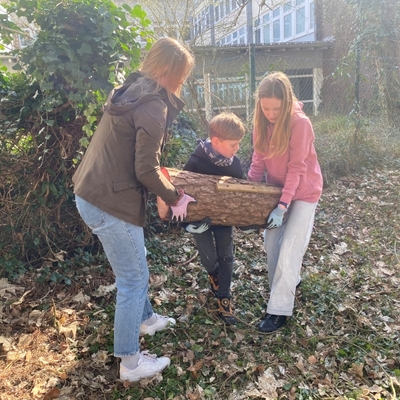 Zwei Sch&uuml;lerinnen tragen gemeinsam einen Kasten oder Nistkasten im Freien.