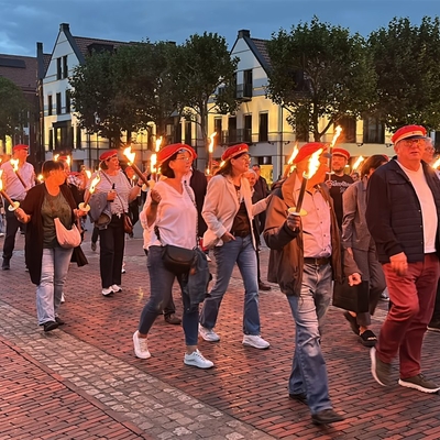 Gruppe von Menschen zieht am Abend mit Fackeln durch die Innenstadt.