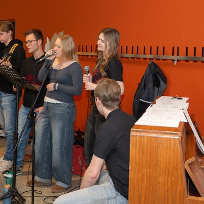 Jugendliche musizieren gemeinsam mit einem Lehrer.