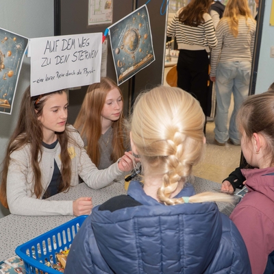 Kinder besuchen eine Mitmachstation und schauen sich gemeinsam einen Bildschirm und Materialien an.