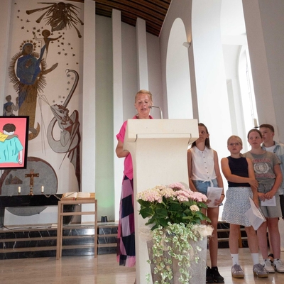 Eine Frau spricht in einer Kirche, neben ihr stehen Kinder.
