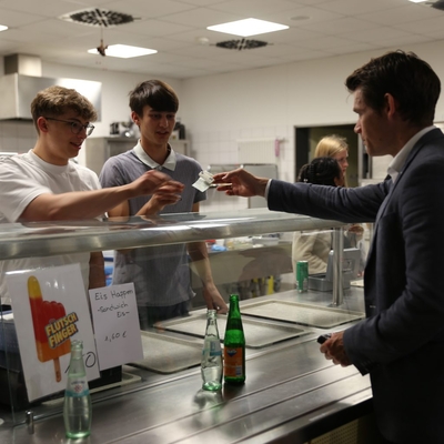 Ein Mann bezahlt sein Getr&auml;nk an einem Verkaufstresen in einer Mensa.