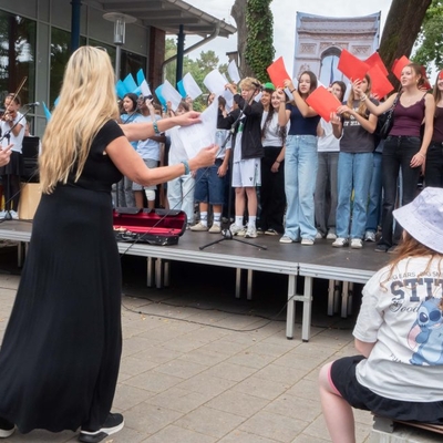 Ein Schulchor bei einer Darbietung auf einer B&uuml;hne im Au&szlig;enbereich.