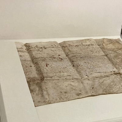 Altes handschriftliches Dokument liegt ausgebreitet auf einer hellen Fl&auml;che.