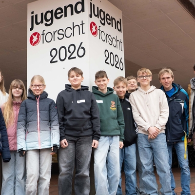Sch&uuml;lergruppe posiert vor einer Wand mit dem Schriftzug Jugend forscht.