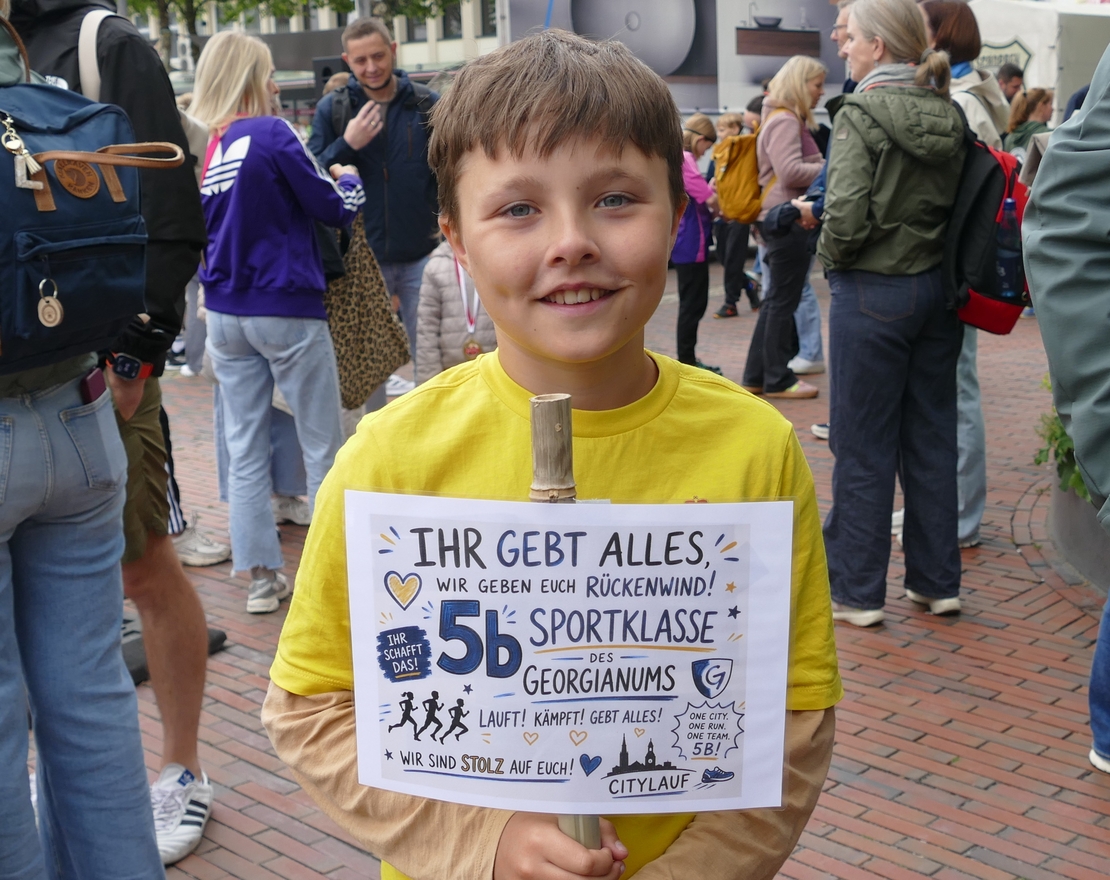 Bennet zeigt sein gro&szlig;artiges Plakat und feuert seine Klasse an.