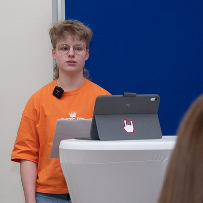 Ein Jugendlicher pr&auml;sentiert mit Tablet vor Publikum.